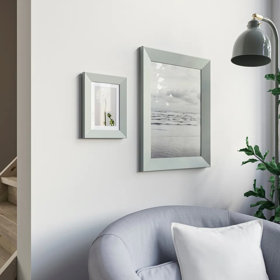 Modern living room with blue couch, nature photo frames, grey lamp.