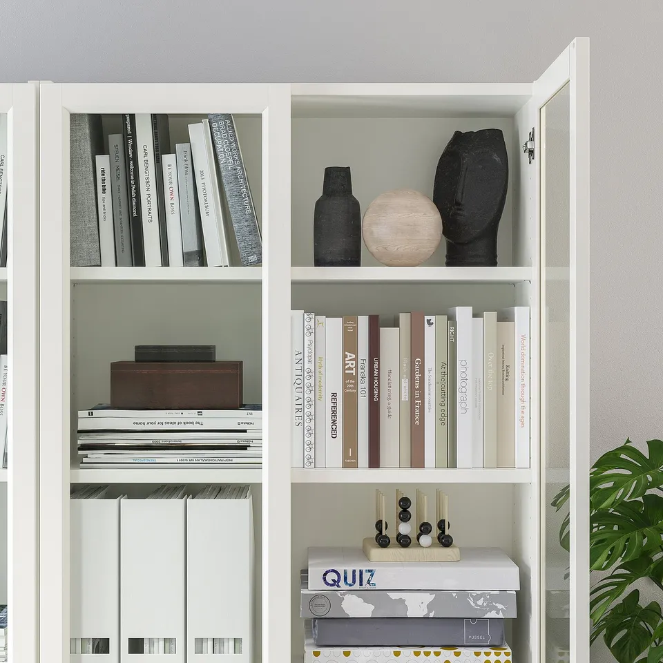 White bookshelf with glass doors; holds books and decorative items; adjustable shelves.