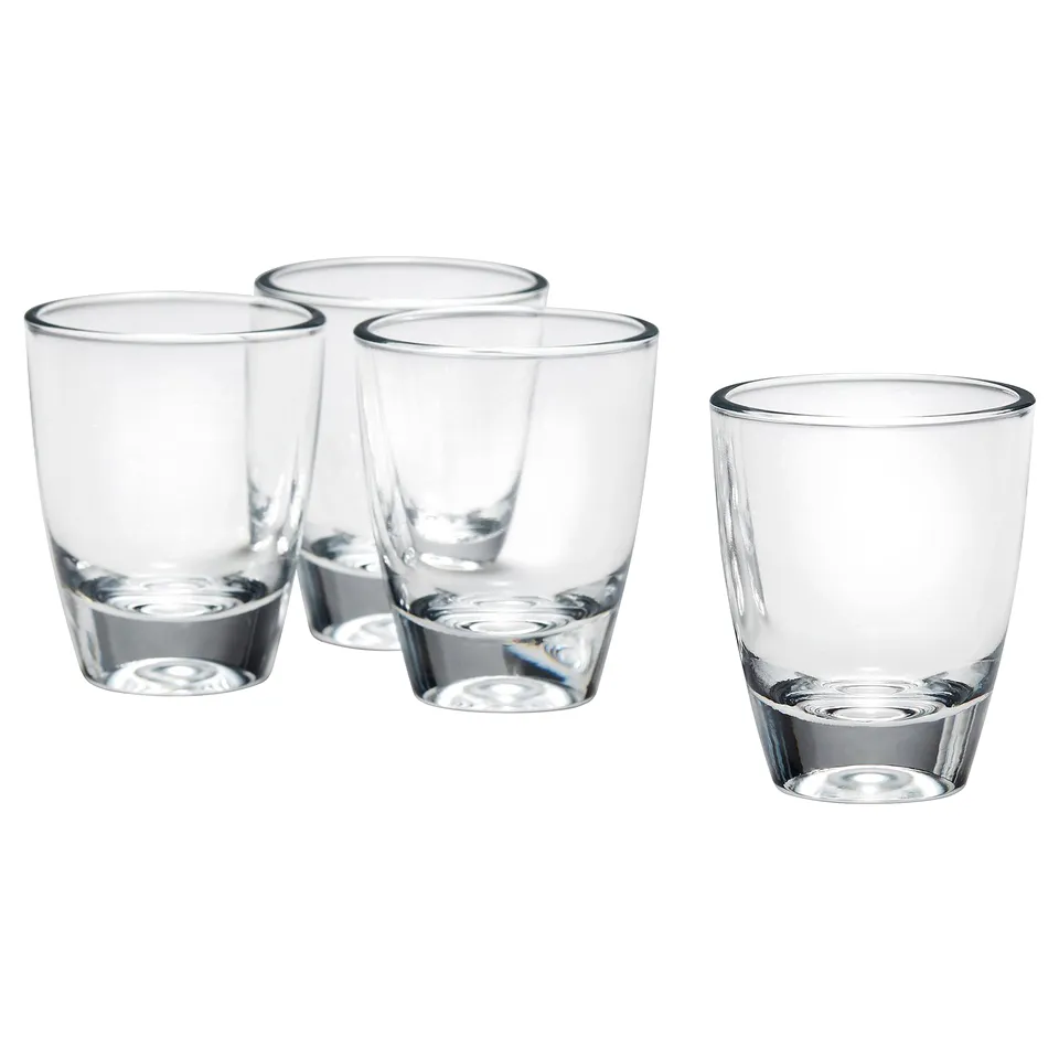 Four clear, small glasses made of glass, arranged in a triangle formation with one on the side, perfect for serving strong drinks.