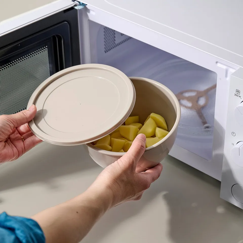 Person placing bowl in microwave from GARNITYREN set.