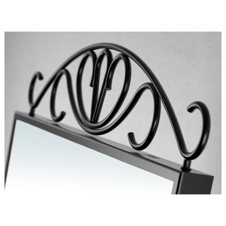 Dark ornate metal arch frame rests atop rectangular mirror, elegant design.