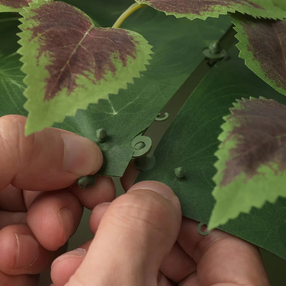 Hands assembling FEJKA plant panels with clicks.