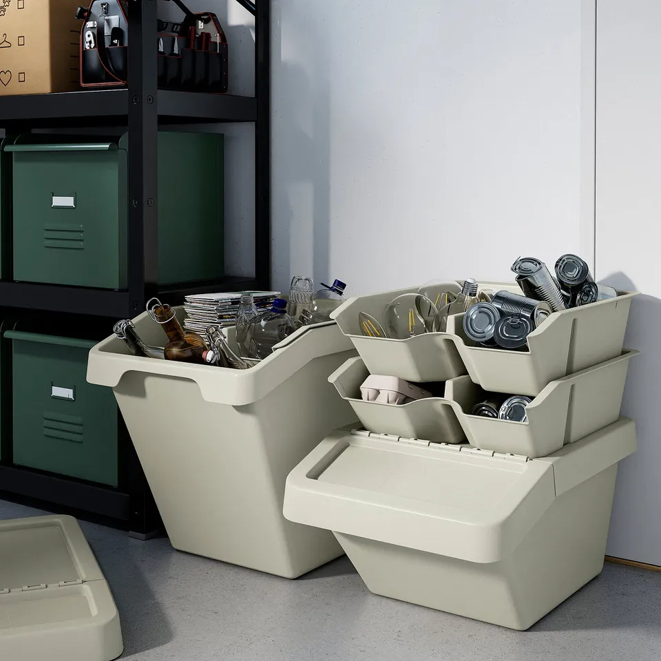 Stacked white recycling bins under shelves, filled with metal cans and plastic bottles, demonstrating waste sorting.