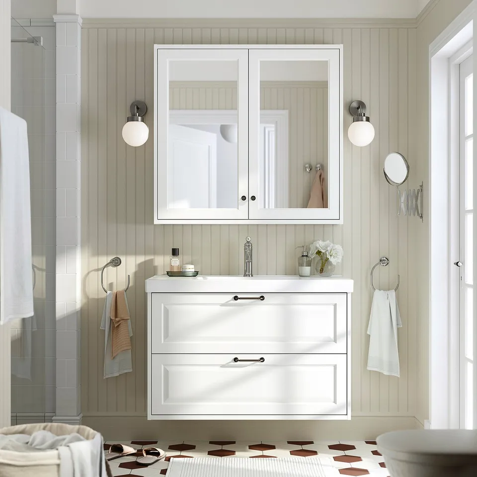 Modern white bathroom with TÄNNFORSEN vanity, mirror cabinet, sink, drawers, and sconces.