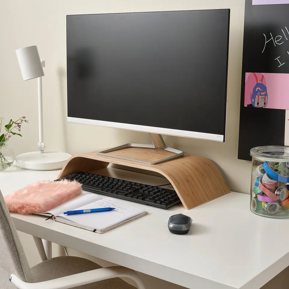 Bamboo monitor stand with computer, accessories, and desk items.