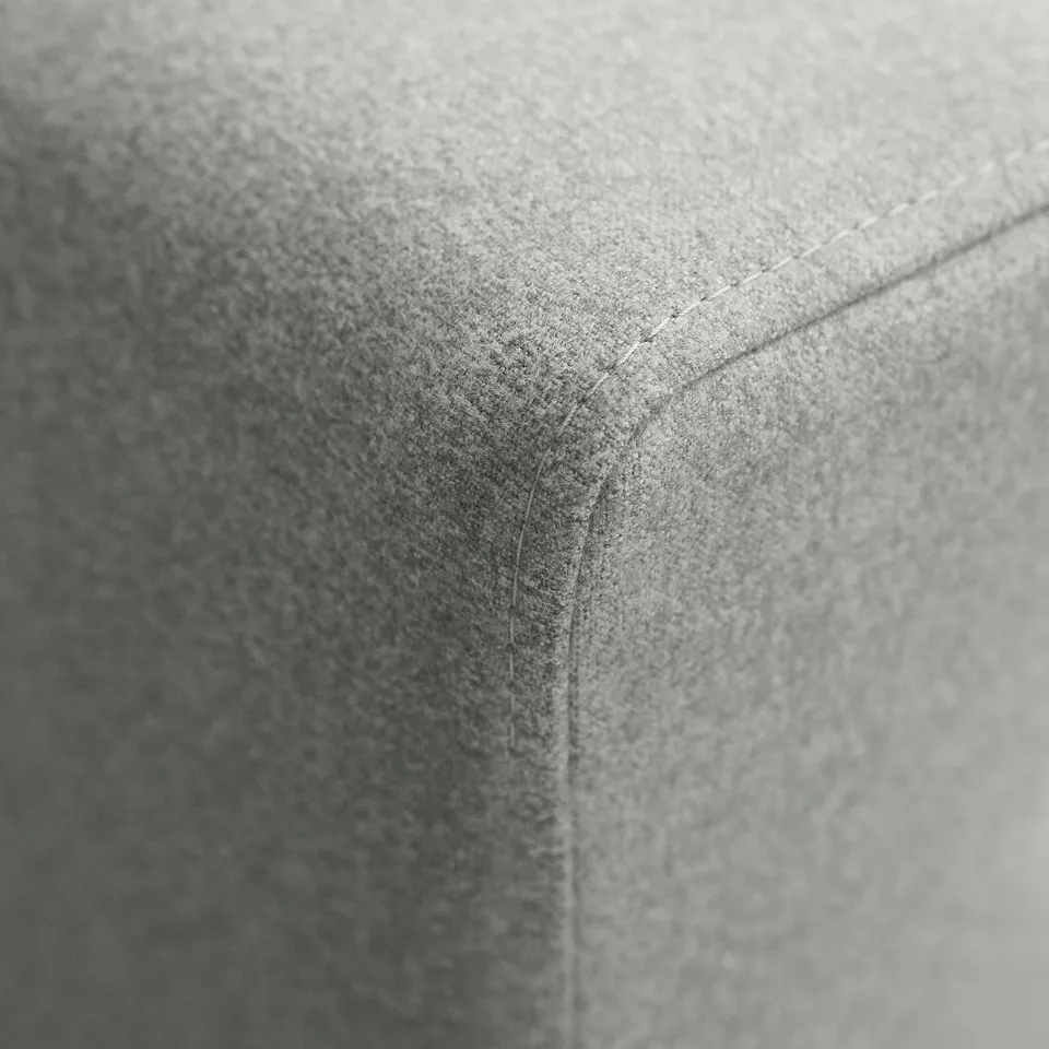 Close-up of textured, grey upholstered footstool edge, showcasing quality stitching.