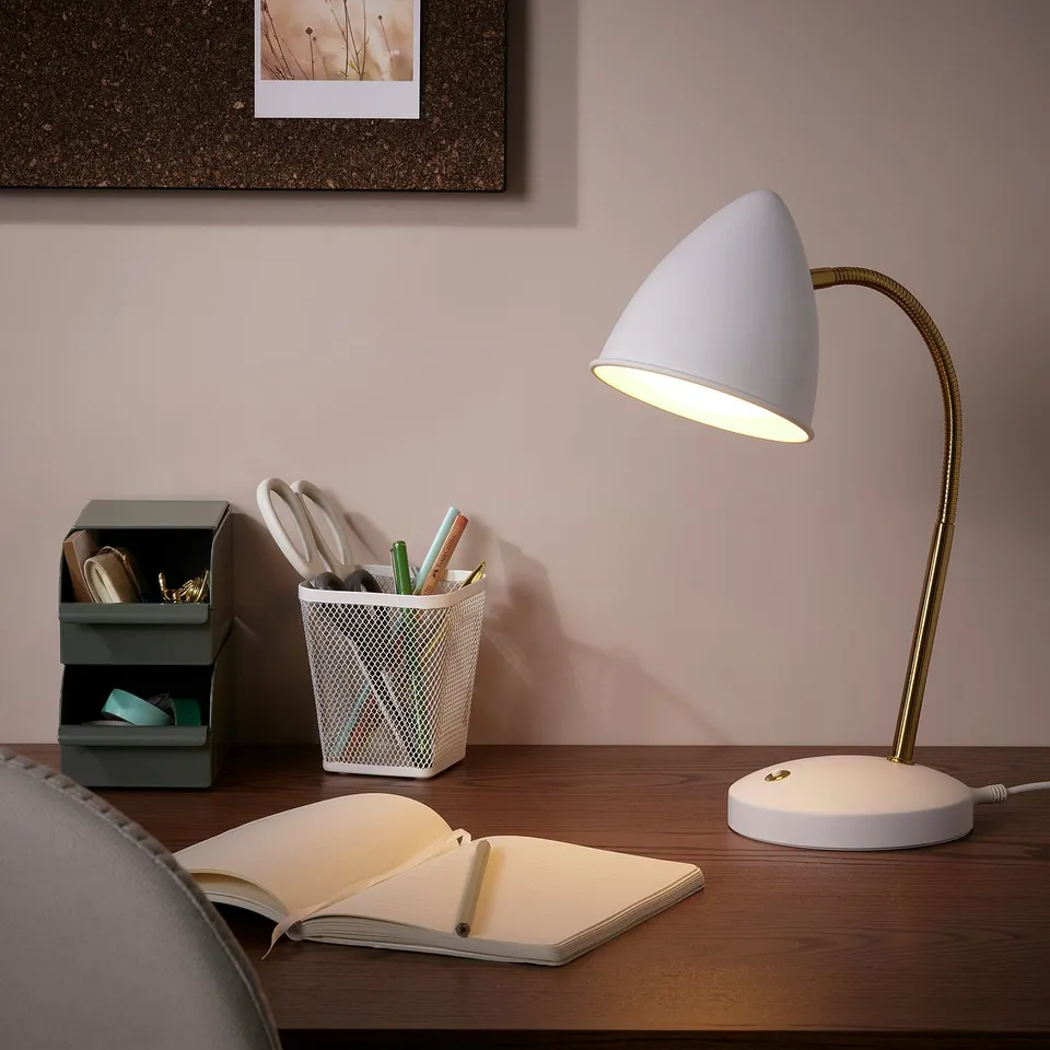 Golden lamp illuminates desk with book, pen holder, and organiser - cosy workspace.