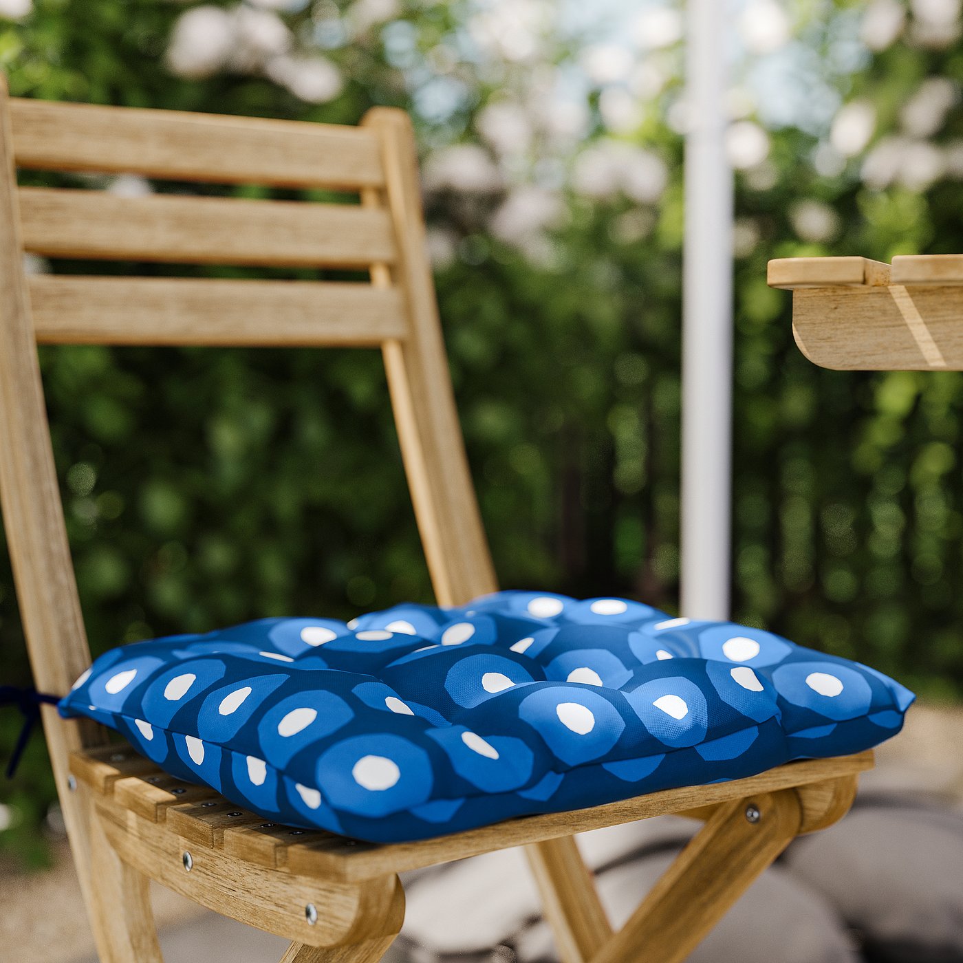 A blue and white polka dot cushion on a wooden chair.
