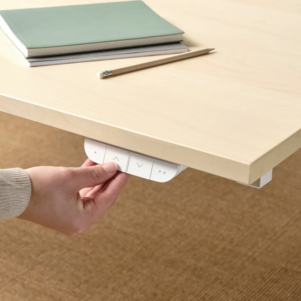 Person adjusting height of sit-stand desk using hand control.