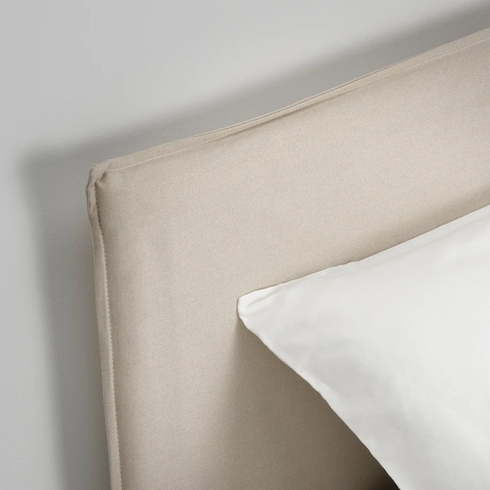 Close-up of neatly upholstered headboard on modern bed, showing fine stitching and high-quality fabric.