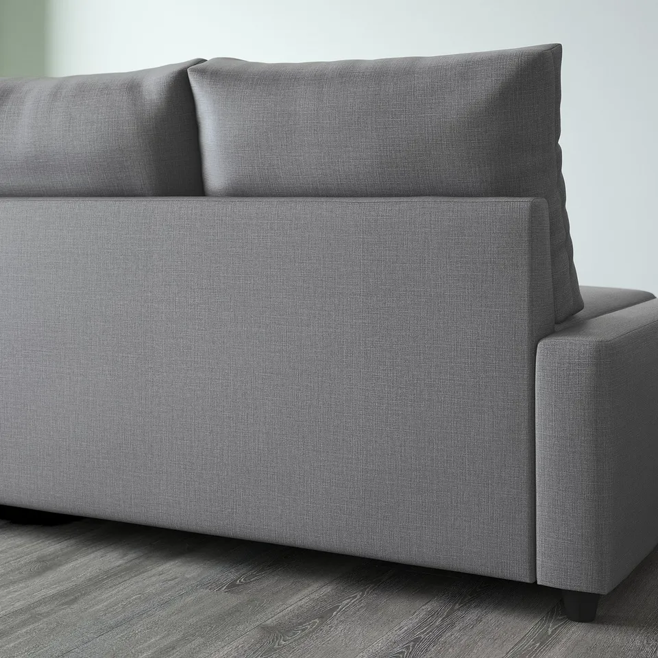 A modern grey multifunctional sofa with a chaise lounge end, part of the FRIHETEN collection, designed for converting into a comfortable bed.