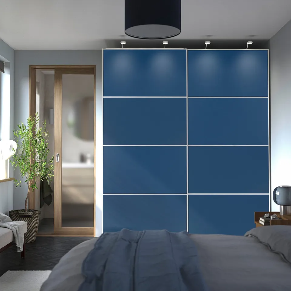 Modern bedroom with large blue PAX wardrobe, grey bed, and plant near entrance.