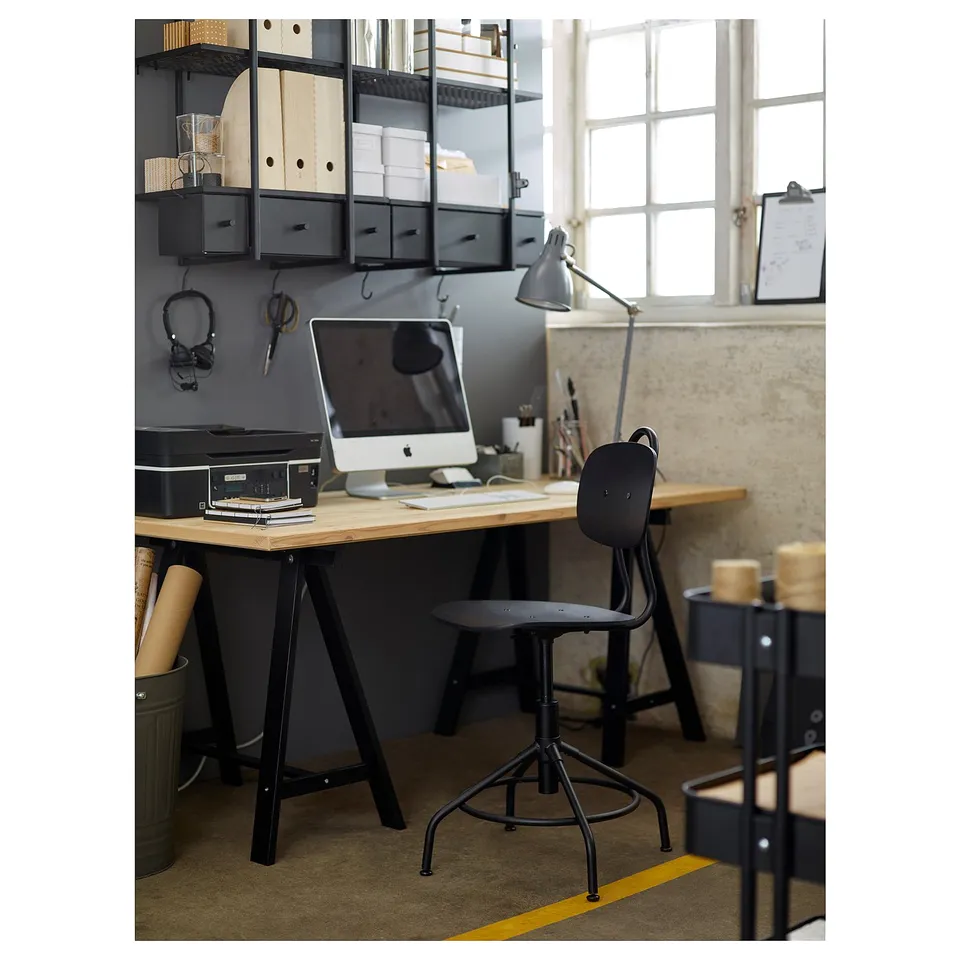 Modern industrial-style office setup featuring a black desk, wooden chair with metal base, large window, and shelves.