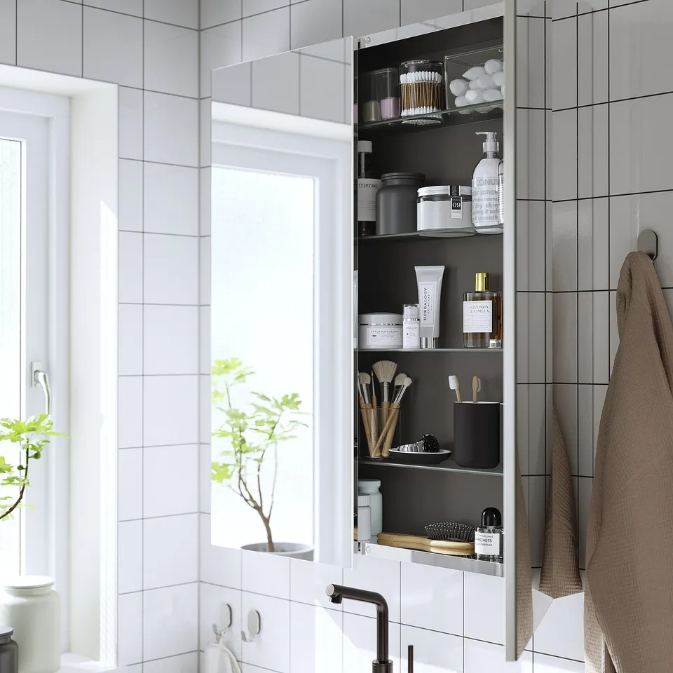 Mirrored bathroom cabinet with toiletries and spacious reflection.