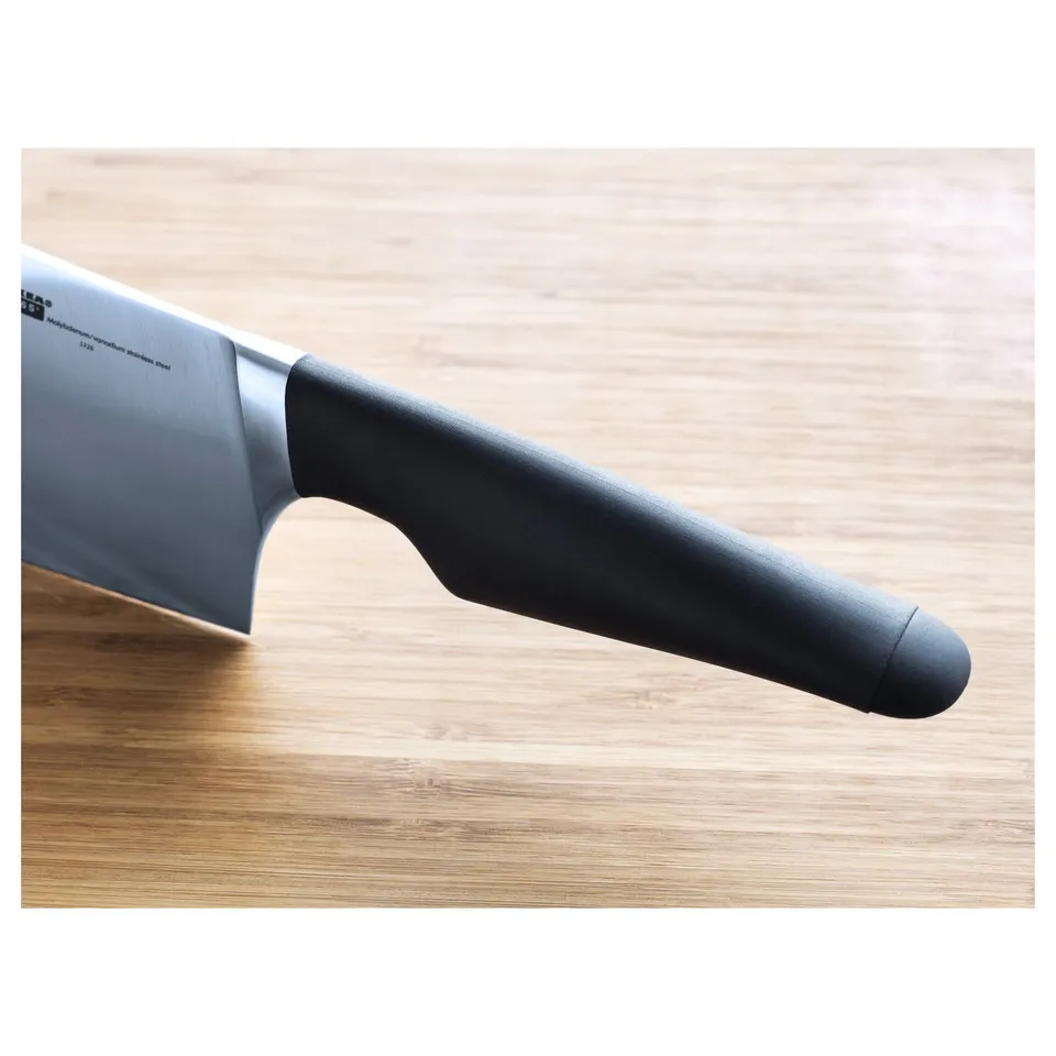 Sharp, high-quality knife with a black handle resting on a wooden surface. Made of durable stainless steel, ensuring long-lasting sharpness.