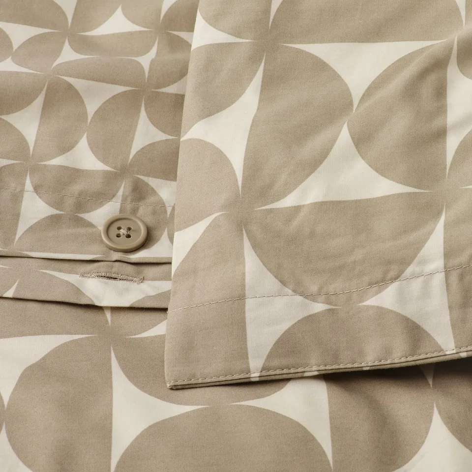 Close-up of duvet cover with envelope closure and button, featuring graphic pattern in grey-beige and off-white tones.