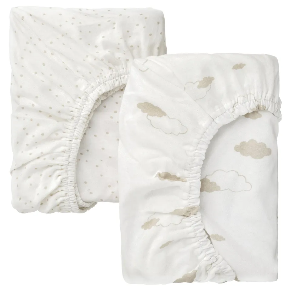 Two white baby fitted sheets, one with beige dots, the other with beige clouds, folded.