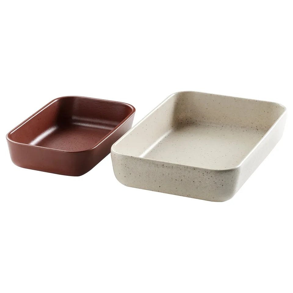 Two rectangular ceramic baking dishes, one red, one beige with speckles, placed side by side.