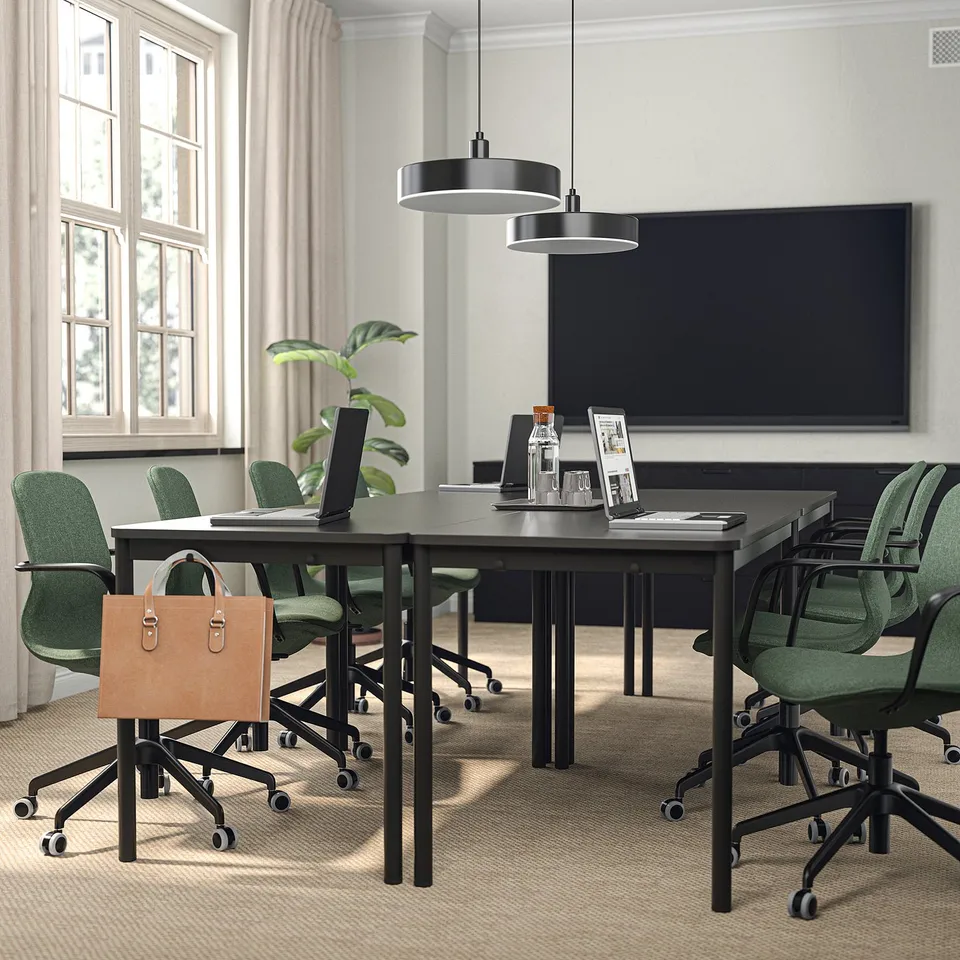 Modern office with green chairs, laptop, black lights, and tv.