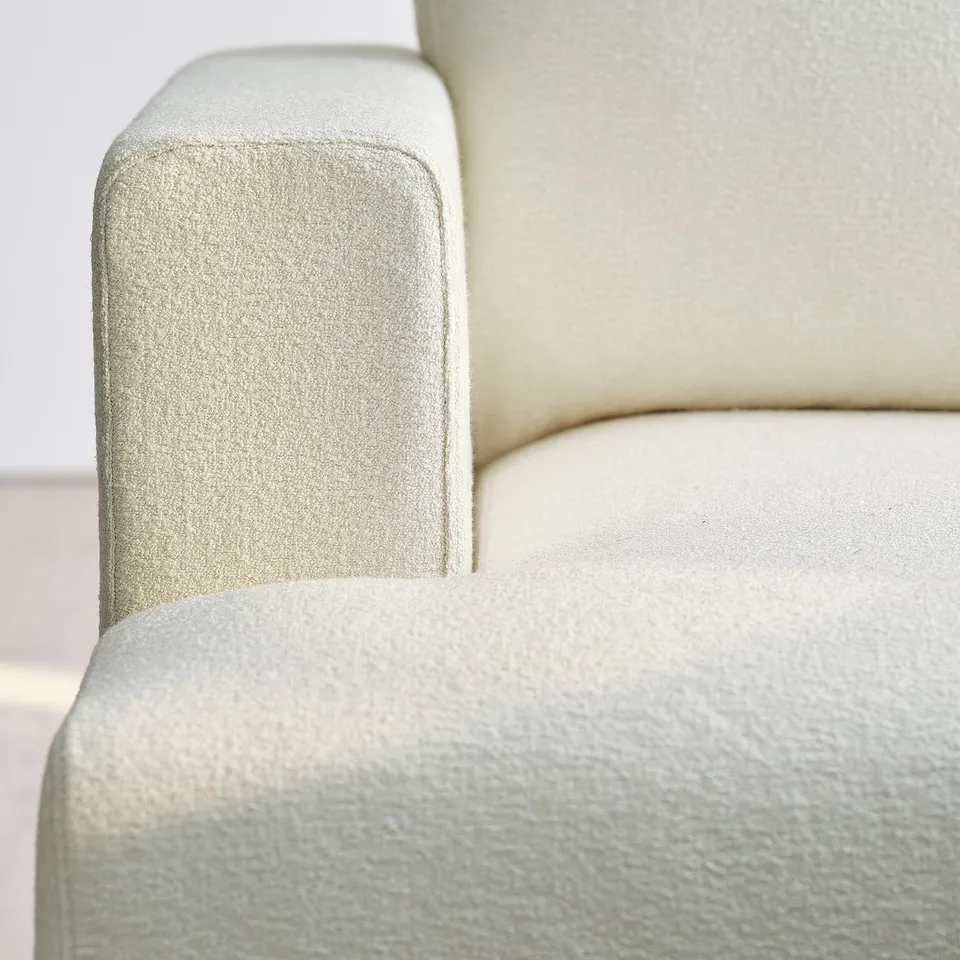 Close-up of a stylish, comfortable sofas armrest with a soft, textured cream fabric.