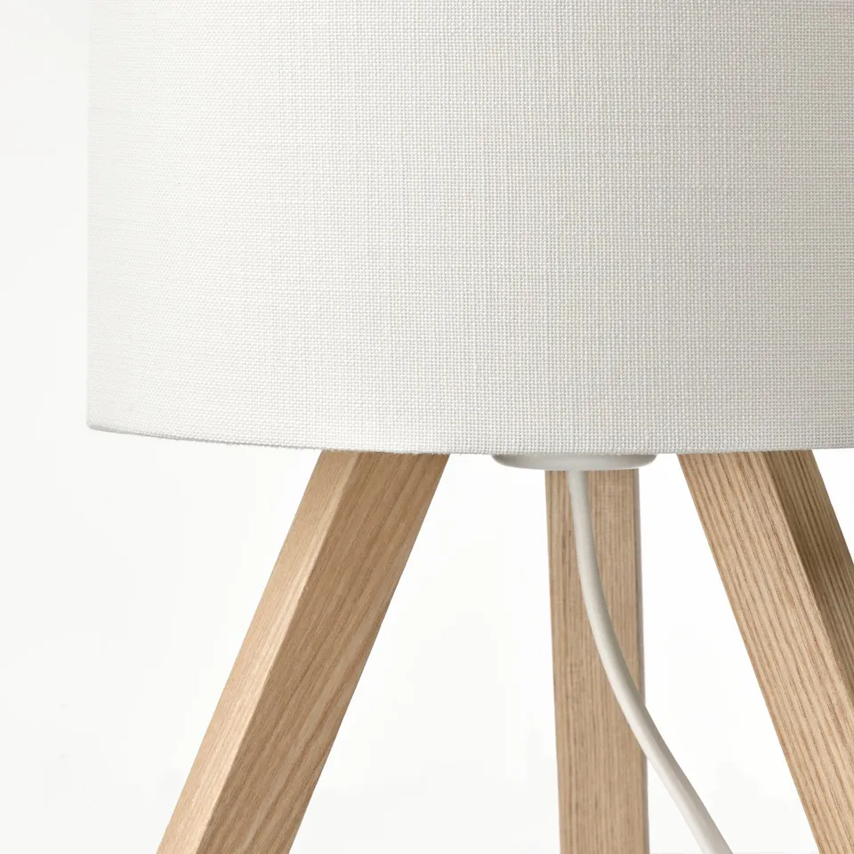 Modern table lamp with white shade and light wood legs.