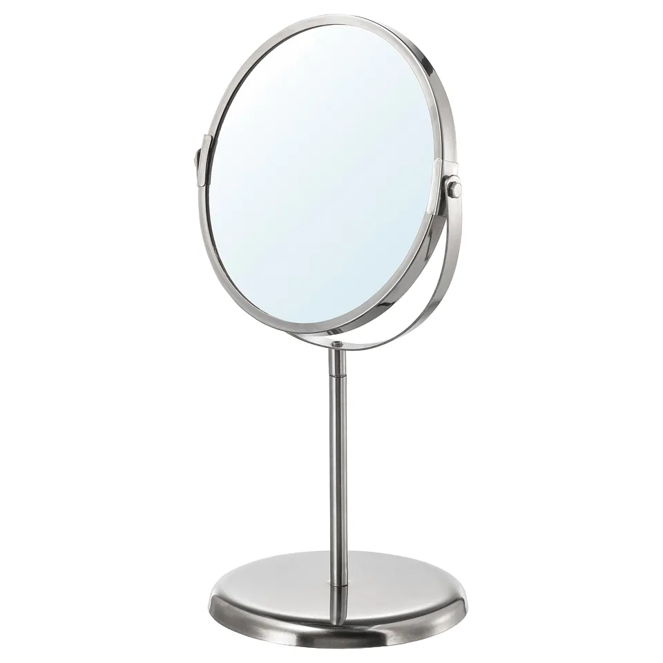 Displays the TRENSUM mirror. It a sleek, round, stainless steel design with a base, suitable for bathroom use.
