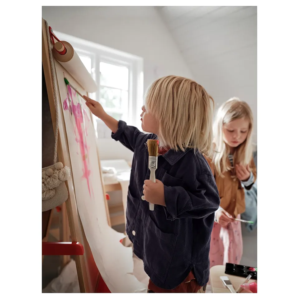Two kids painting at an easel with supplies.