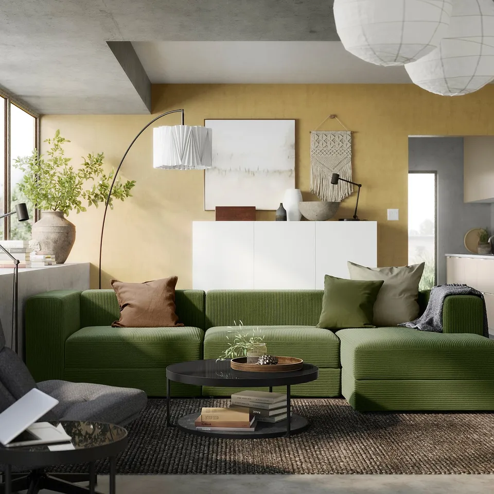 Modern living room with olive-green sectional sofa, cushions, coffee table, large window, lamps, wall art, and yellow walls.