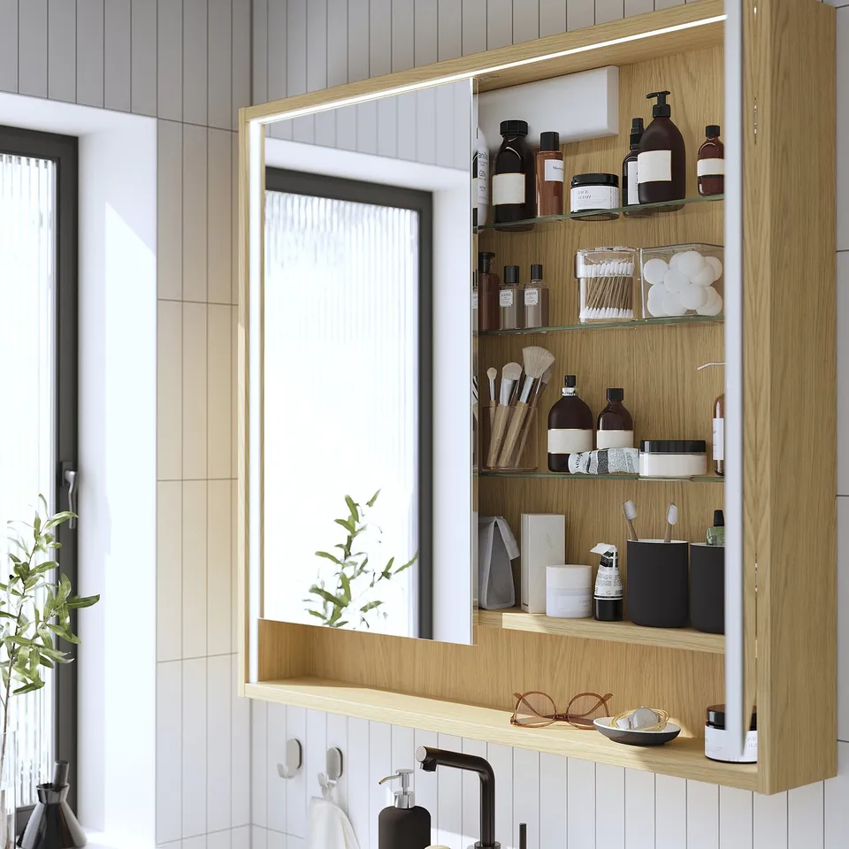 Wooden mirror cabinet with built-in lighting, organising toiletries and makeup. Showing its practical storage and lighting functions.