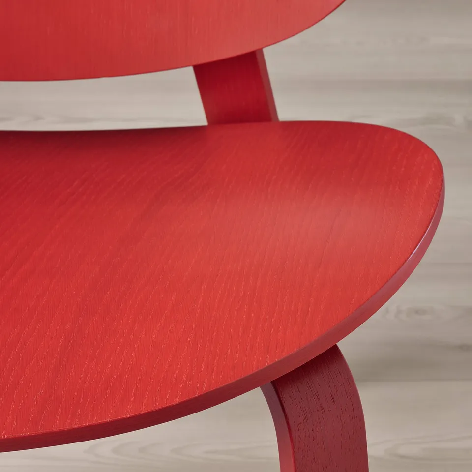 Close-up of the smooth, vibrant red surface of the modernist FRÖSET chair.
