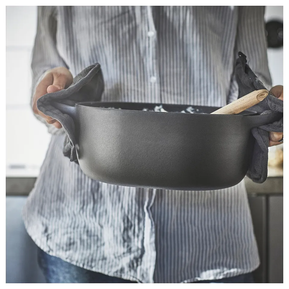 Person holding black VARDAGEN enamel cast iron pan.