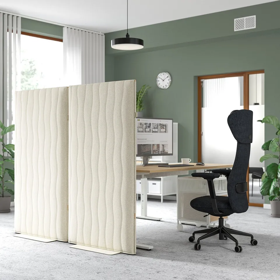 MITTZON acoustic screen divides modern office spaces. Tall, beige, with natural sand ripple pattern, absorbs sound, stands beside black desk chair.