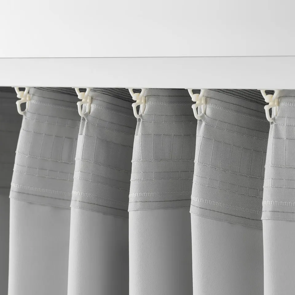 Close-up of grey VILBORG curtains with linear texture, showing hooks and pleats for easy hanging and room darkening.