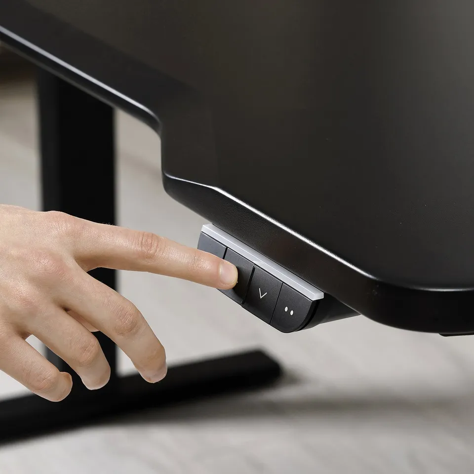 Hand adjusting electric standing desks control panel, ensuring smooth and durable operation.