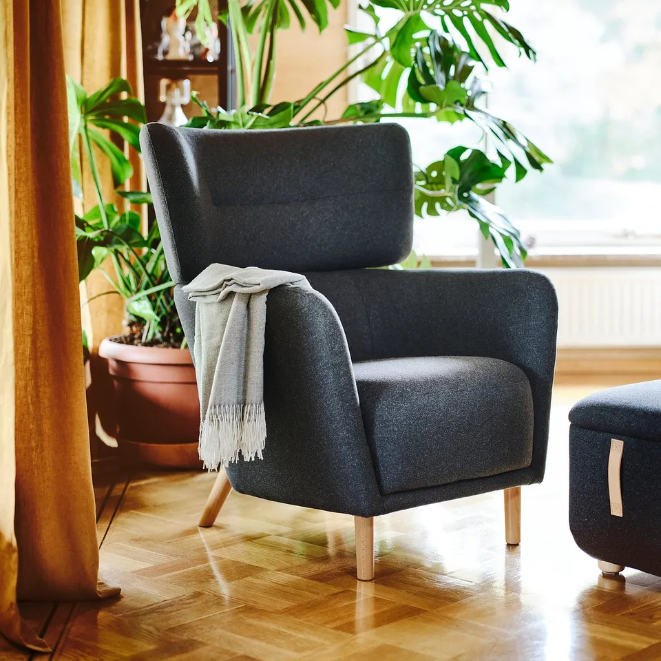 Cosy grey OSKARSHAMN chair, large & plush, by window. Lush plants nearby.