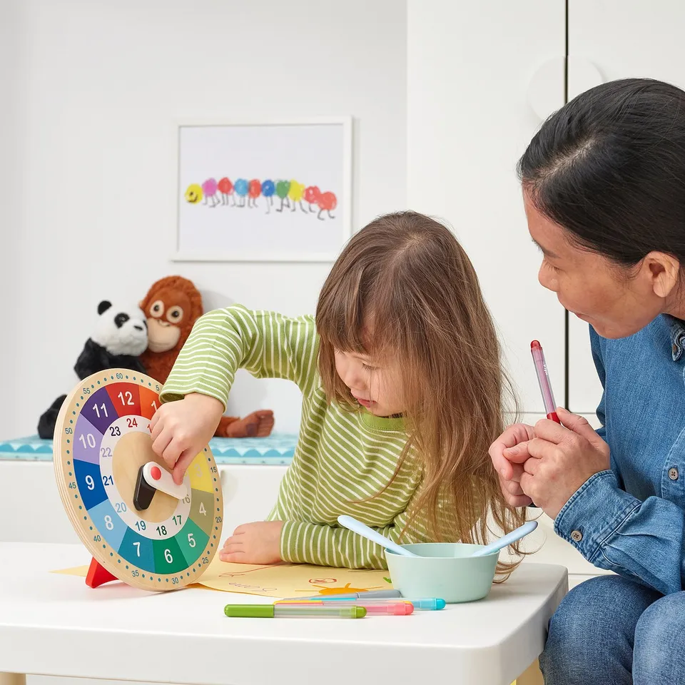 Child and adult using colourful, educational clock to learn time.