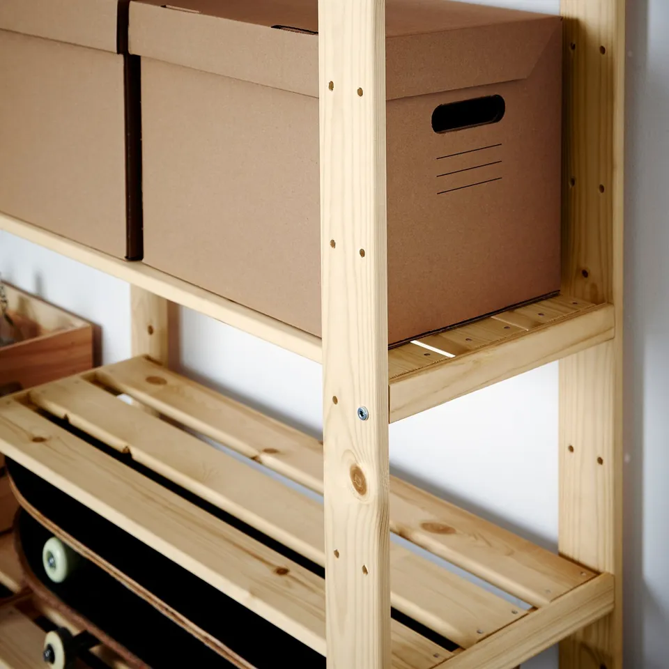 A wooden storage unit with thick shelves holds cardboard boxes. Its sturdy, suitable for heavy loads, and can be customised with paint or stain.