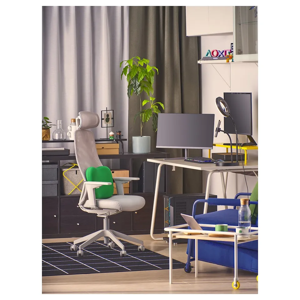 A modern home office with a grey ergonomic chair, desk setup with dual monitors, and a blue laptop on a small table.