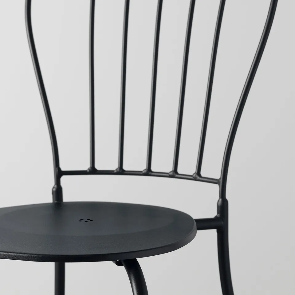 Modern stackable metal chair with intricate back design, suitable for outdoor use. Great for gardens or patios.