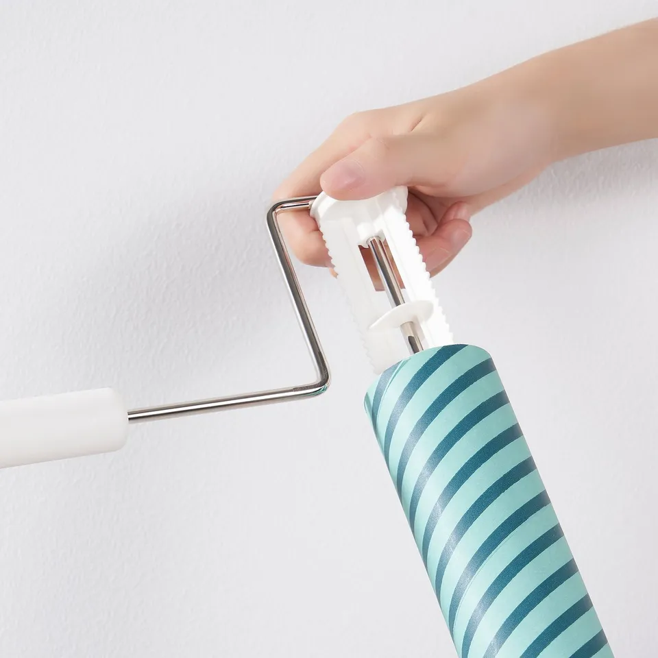 Hand holding PEPPRIG lint roller, removing lint with striped roller refill.