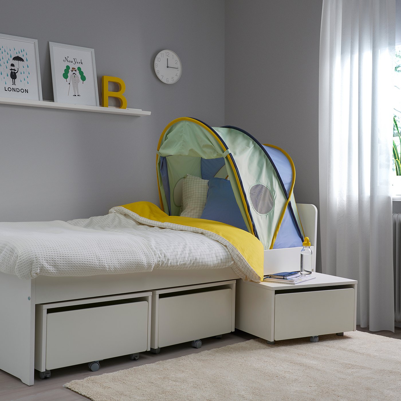 Kids tent in green & yellow, fits on bed with storage. Open with pillows, side table, grey wall posters.