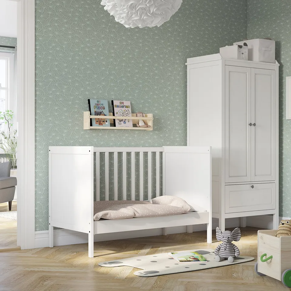 Bright nursery with white SUNDVIK cot, light green wallpaper, soft rug, and wooden storage. Cot is central and large.