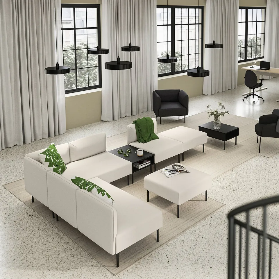 Modern office lounge featuring LILLEHEM white modular sofa, black coffee tables, and dark armchairs, accented with green decor.