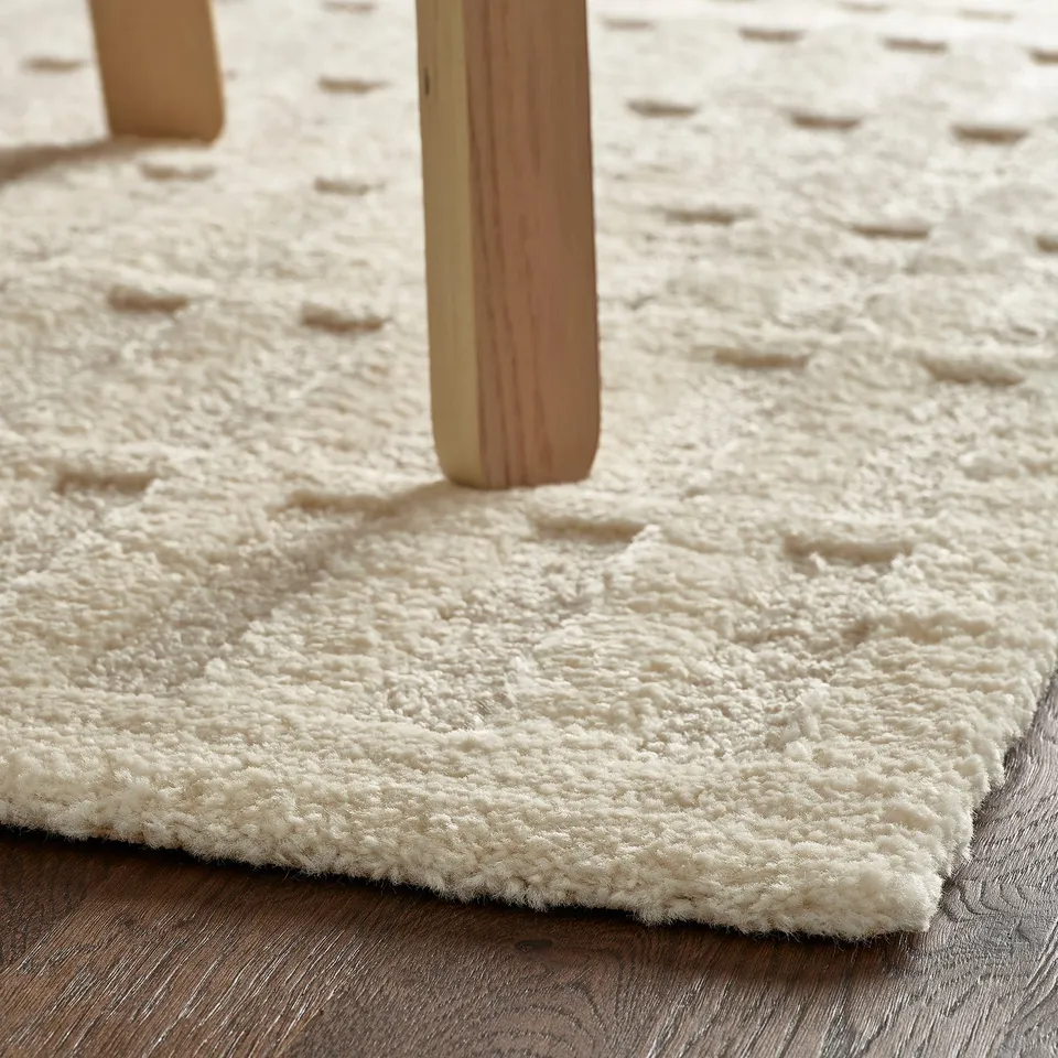 Thick white shaggy rug under wooden table legs, providing warmth and comfort.