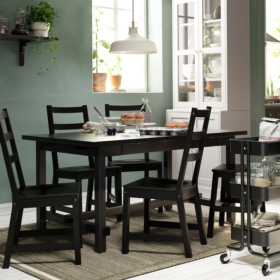 Teal kitchen with black NORDVIKEN dining set for six, plants, pendant light, and glass cabinets.