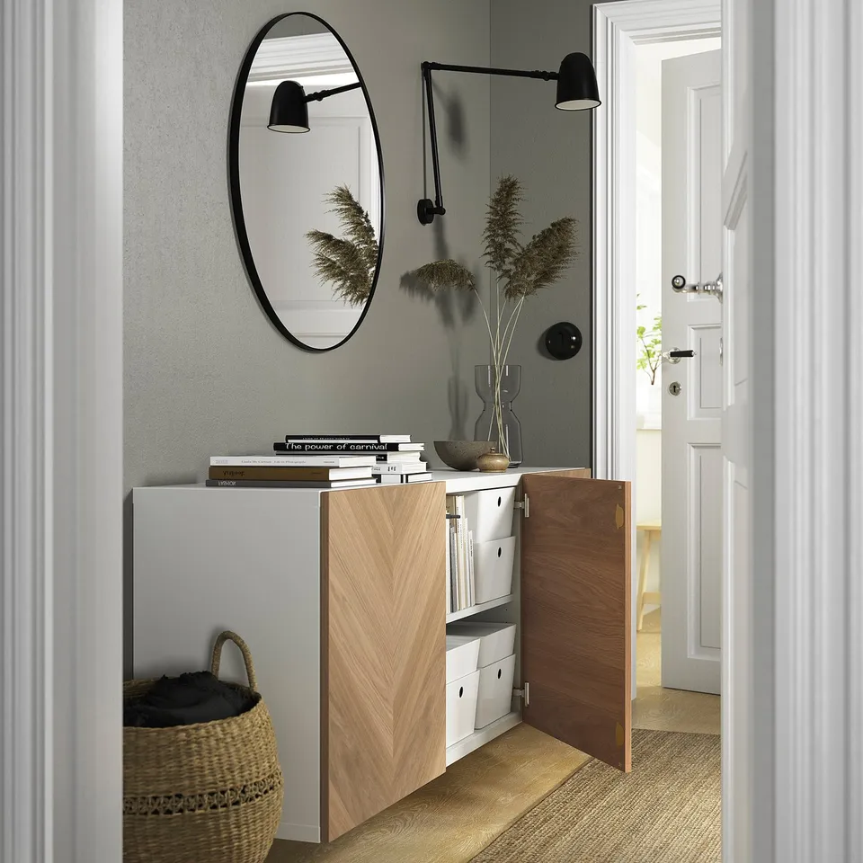 A wall-mounted cabinet with open drawers and shelves; displays books and a vase with plants.