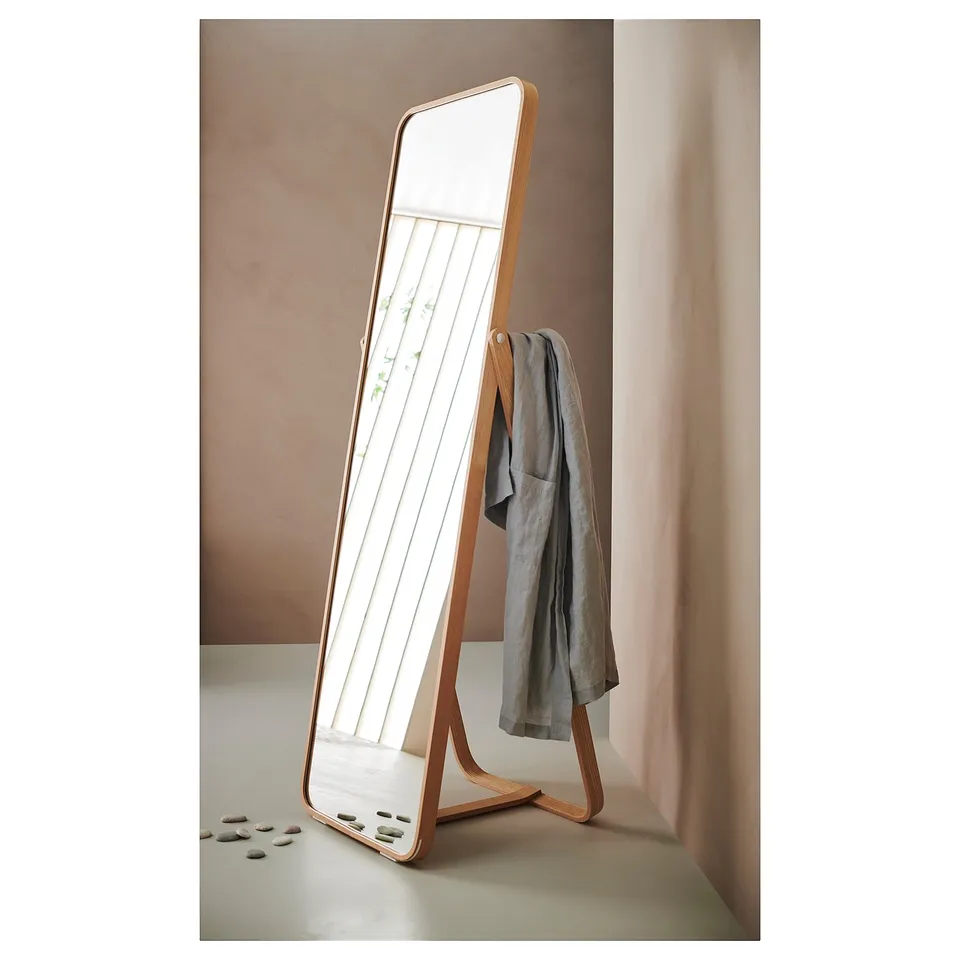 Ikorennes: upright wooden floor mirror, sleek ash finish, hanging garment, soft shapes, reflective glass, leaner design.
