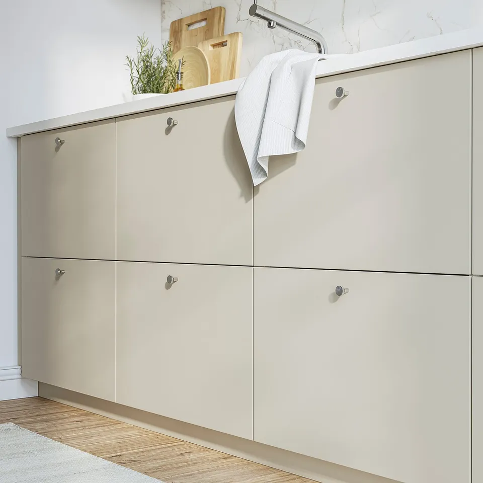HAVSTORP beige cabinet in kitchen. Long, low, beige drawers with metal knobs. Holds cutting boards and towels, fits under counter.