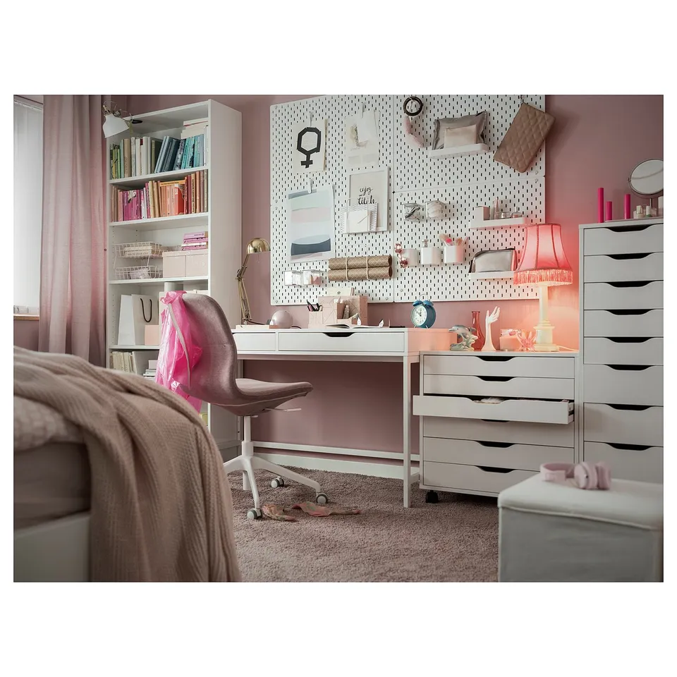 Bedroom with pink walls, grey ALEX desk and storage units, white pegboard, beige chair, and various decorative items.