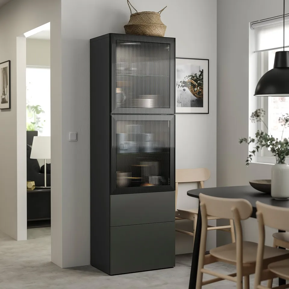 Modern black and glass storage unit in living area, topped with woven basket. Surrounded by wooden chairs and dining table.